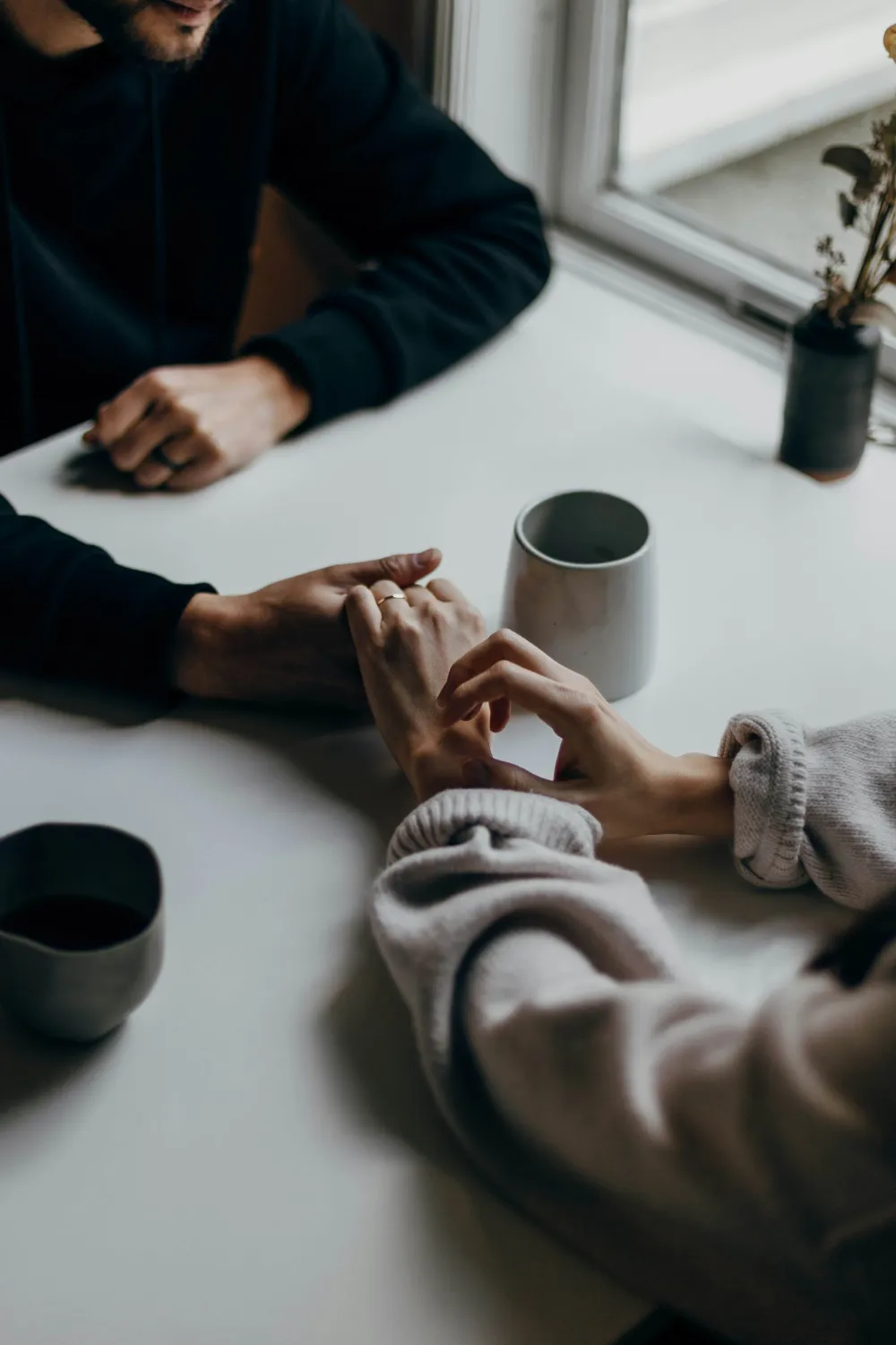 Duas pessoas de mãos dadas à mesa de um café